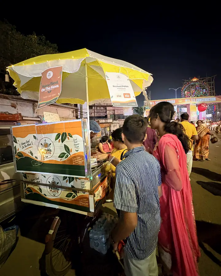 Customers ordering at the lit Pedal Plate cart on a festival evening