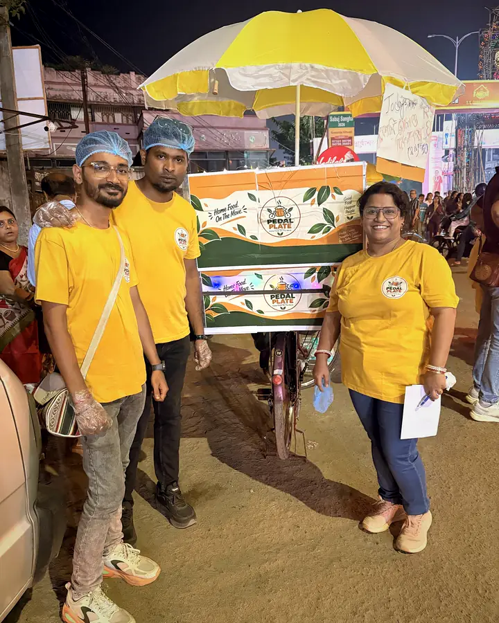 The Pedal Plate crew in uniform beside the branded cycle cart at night