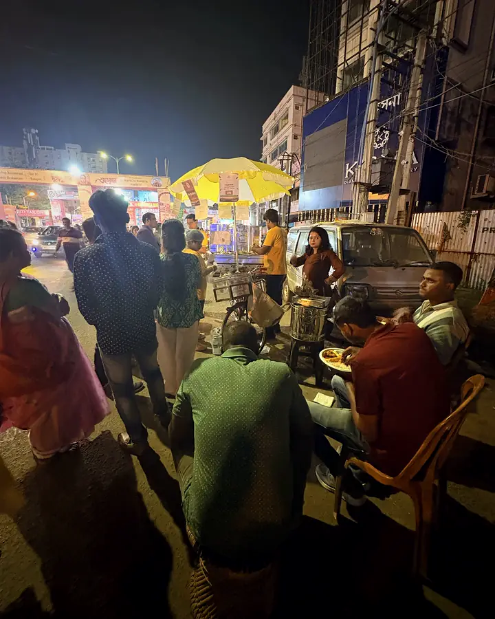 A Pujo night crowd around the lit Pedal Plate cart, with people eating nearby