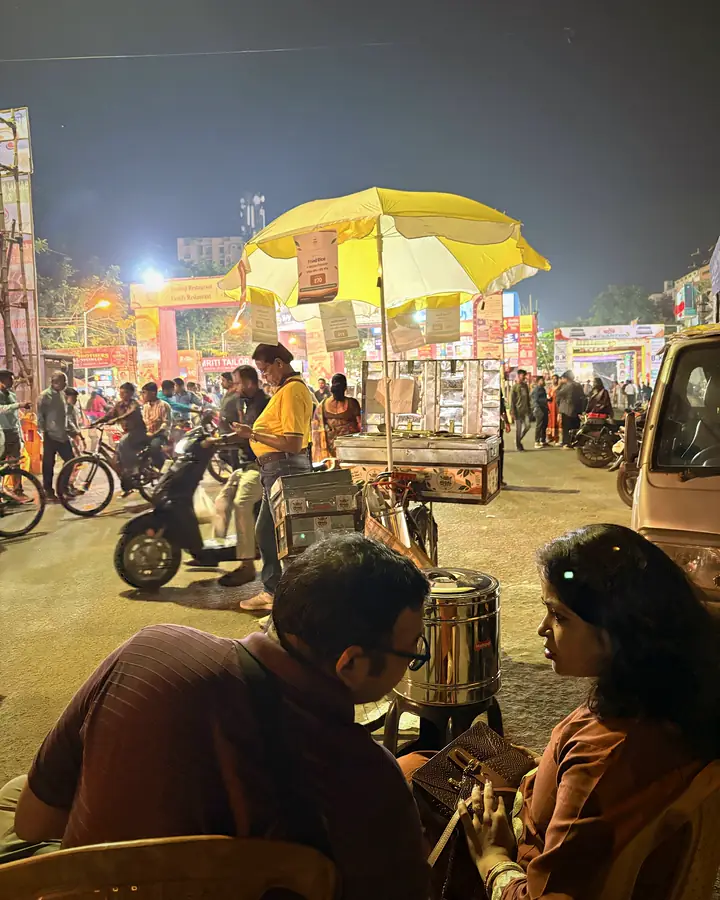 Customers sitting by the roadside near the cart on a busy festival street