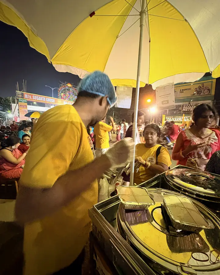 A crew member in a hair net packing foil food boxes at the cart