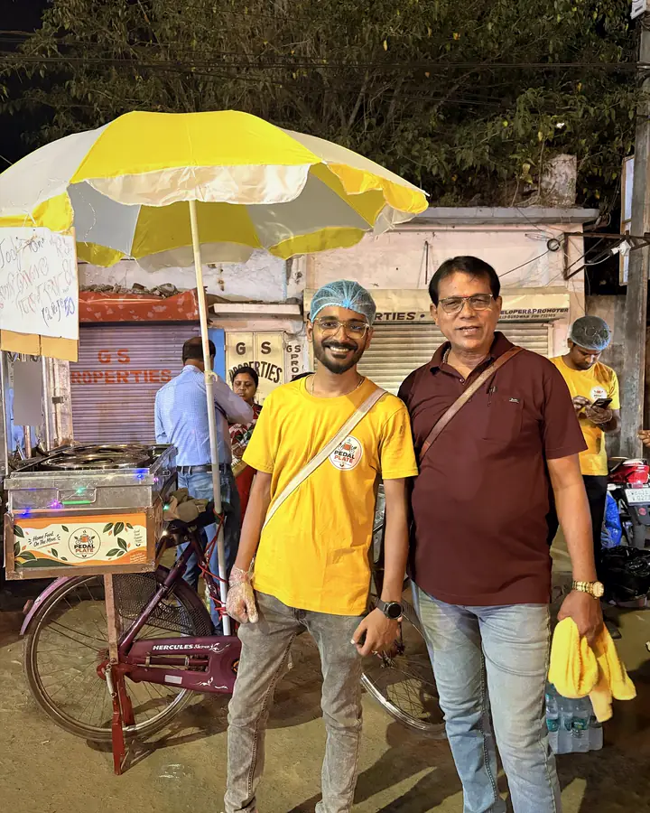 A smiling crew member with a guest beside the Pedal Plate cycle cart